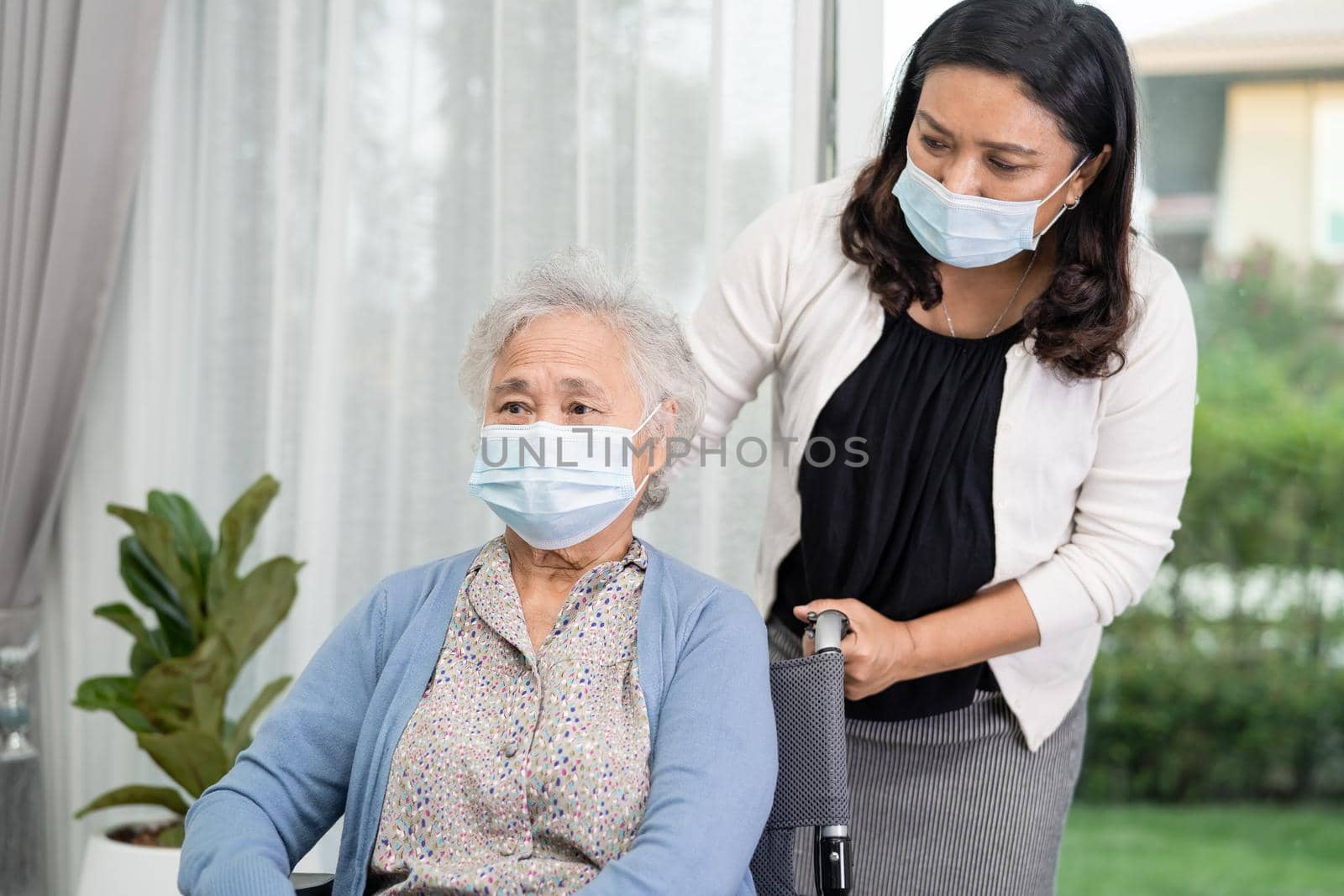 Help Asian senior or elderly old lady woman sitting on wheelchair and wearing a face mask for protect safety infection Covid-19 Coronavirus. by pamai
