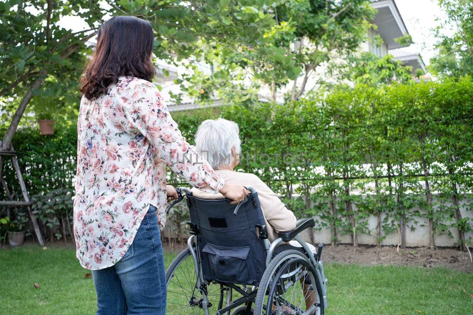 Help Asian senior or elderly old lady woman on electric wheelchair and wearing a face mask for protect safety infection Covid 19 Coronavirus in park by pamai