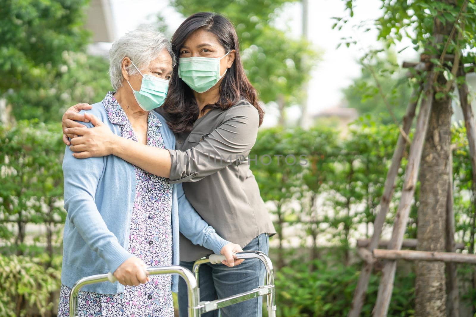 Asian senior or elderly old lady woman walk with walker and wearing a face mask for protect safety infection Covid-19 Coronavirus. by pamai