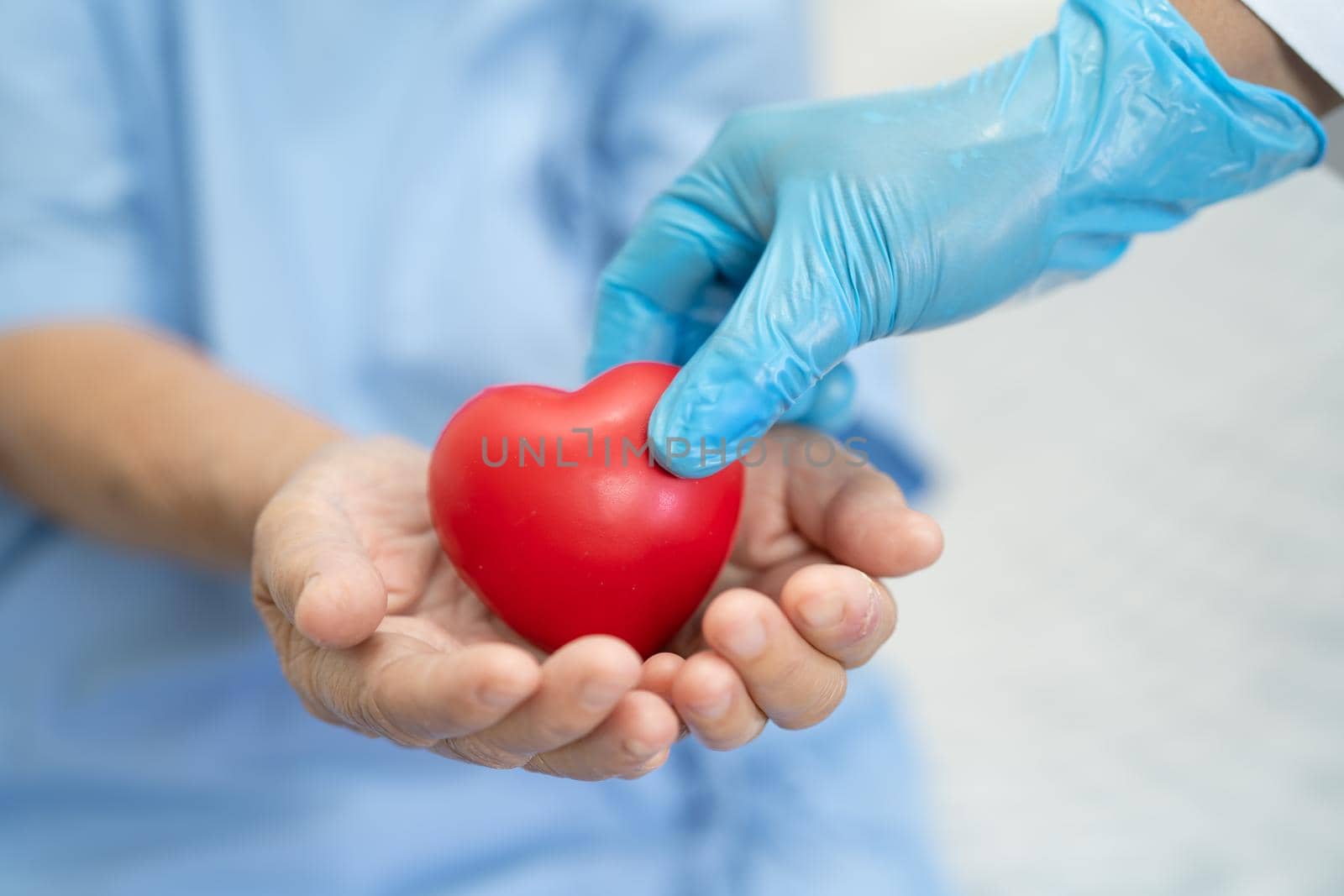 Doctor give red heart to Asian senior or elderly old lady woman patient, healthy strong medical concept