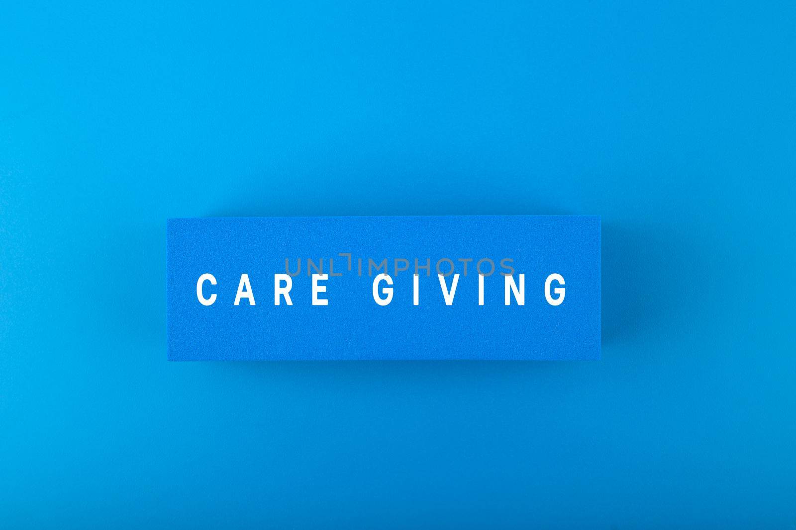 Care giving text written on blue rectangular against blue background by Senorina_Irina