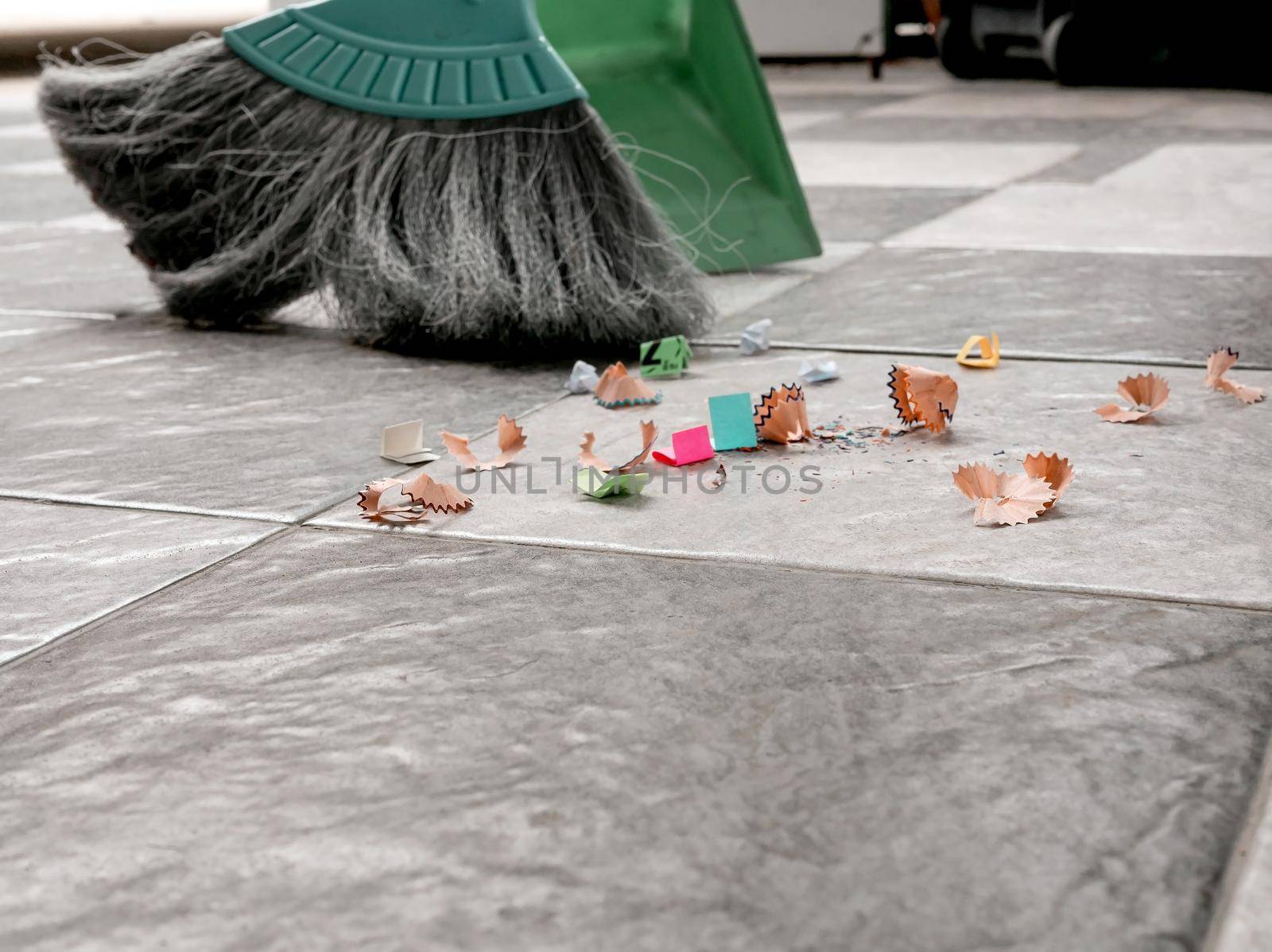 Sweep up scraps of paper and dust on tile floors with a broom and a plastic dustpan.