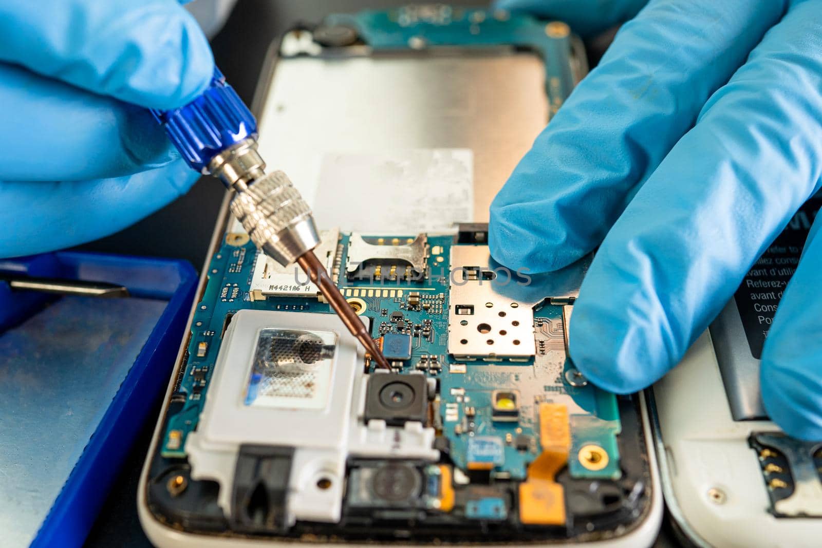 Technician repairing inside of mobile phone by soldering iron. Integrated Circuit. the concept of data, hardware, technology.