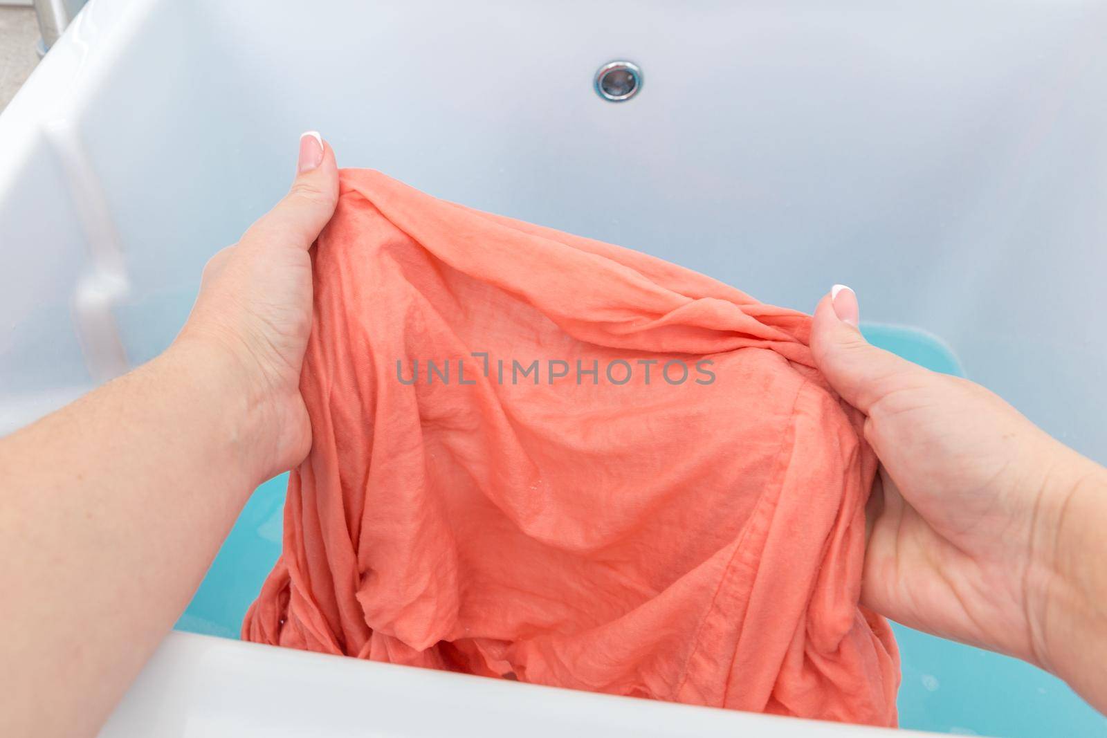 Female hands washing clothes in sink in laundry room