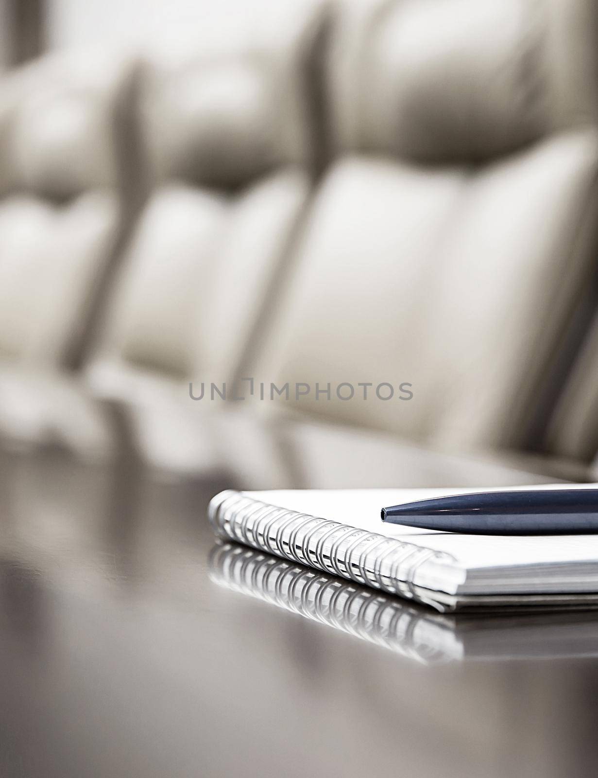 Closeup of notepad kept on table in empty conference room