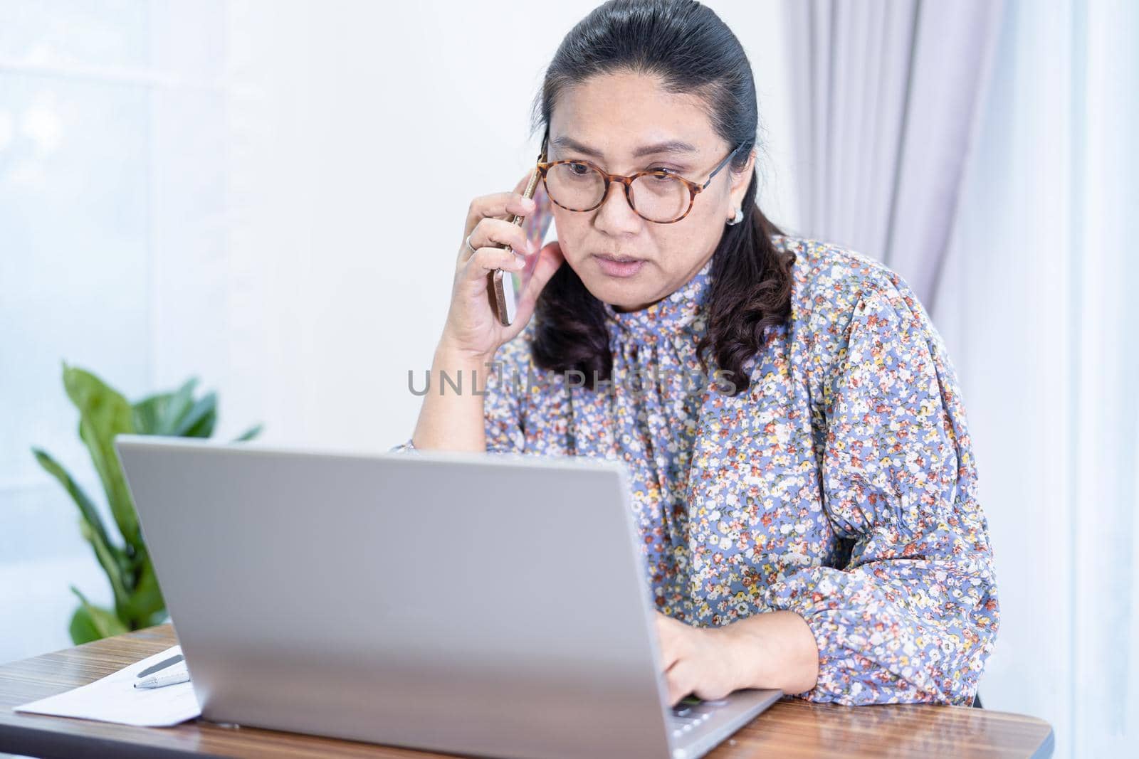Asian lady businesswoman work from home communicate to office by conference video call on laptop, stay at home. by pamai