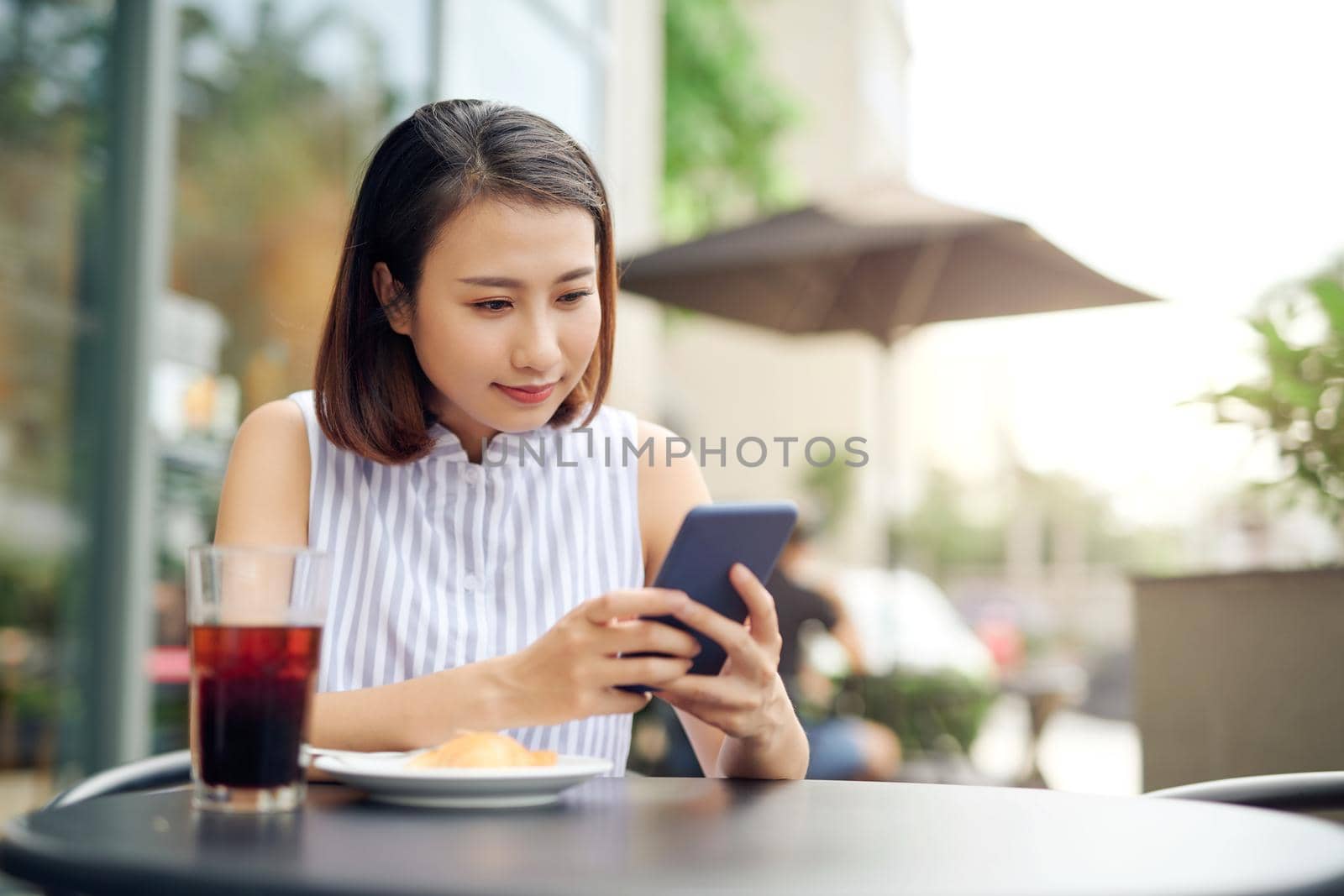 Portrait of beautiful young woman using smartphone while enjoying evening on outdoor coffee shop, copy space