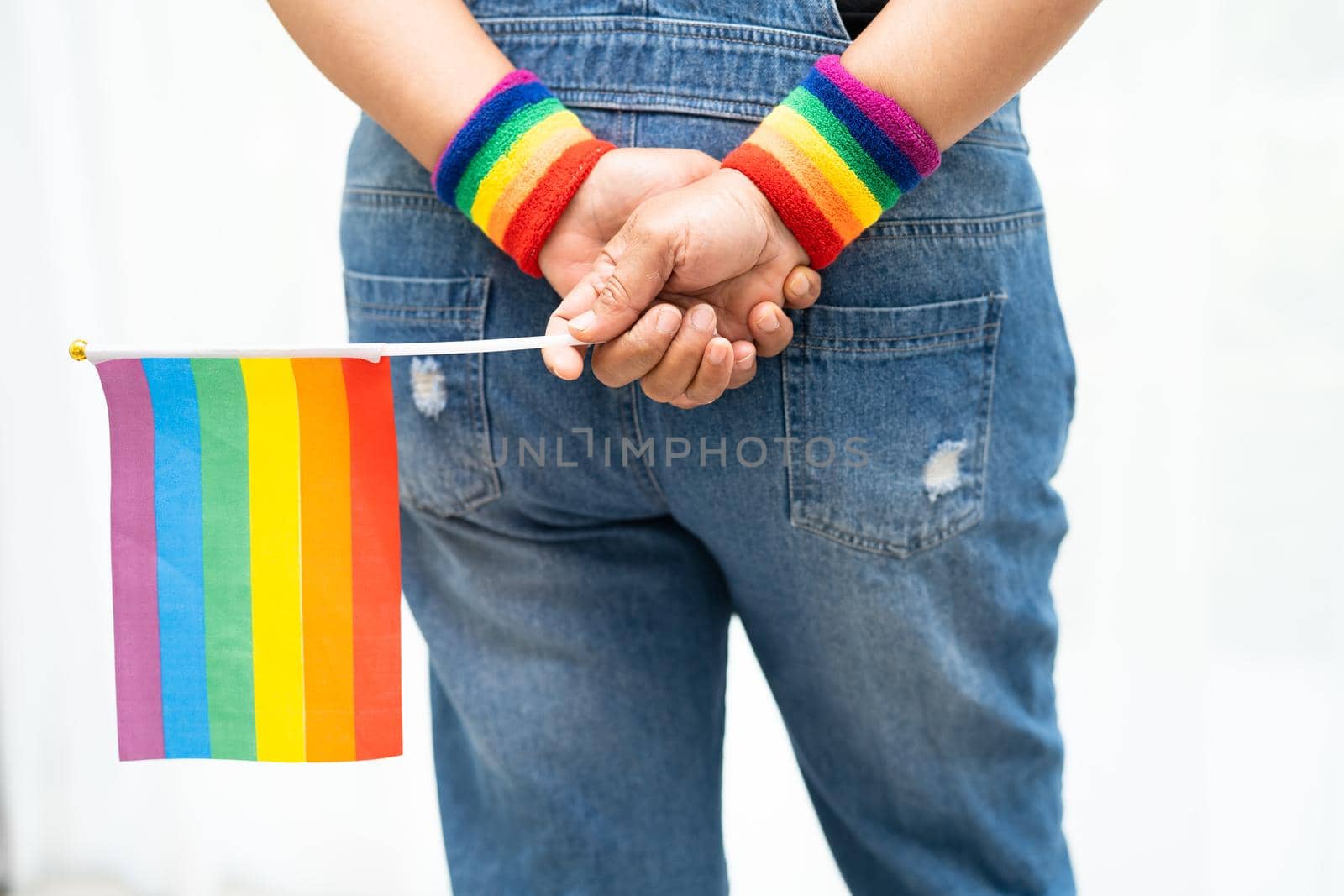 Asian lady wearing blue jean jacket or denim shirt and holding rainbow color flag, symbol of LGBT pride month celebrate annual in June social of gay, lesbian, bisexual, transgender, human rights. by pamai