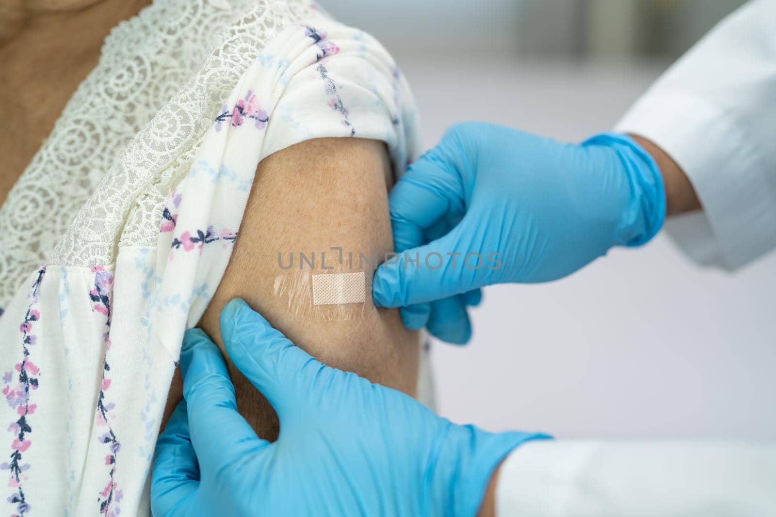 Elderly Asian senior woman wearing face mask getting covid-19 or coronavirus vaccine by doctor make injection.