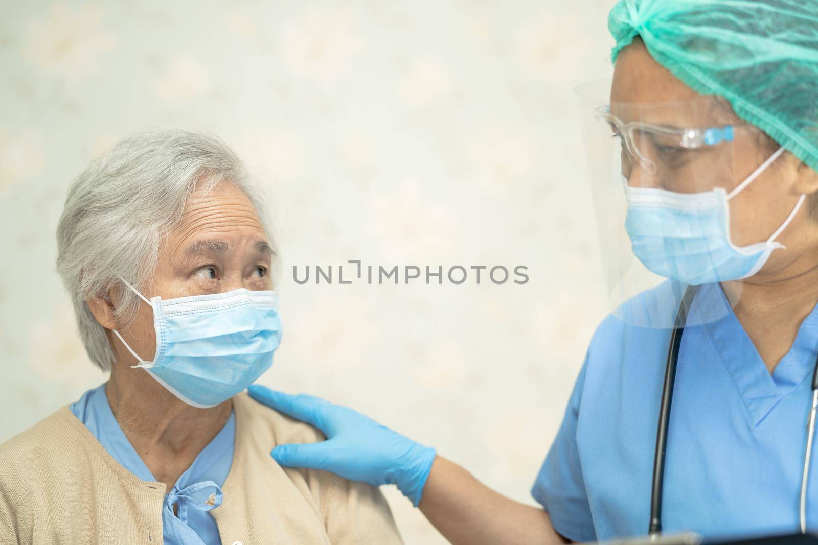 Doctor using stethoscope to checking Asian senior or elderly old lady woman patient wearing a face mask in hospital for protect infection Covid-19 Coronavirus. by pamai
