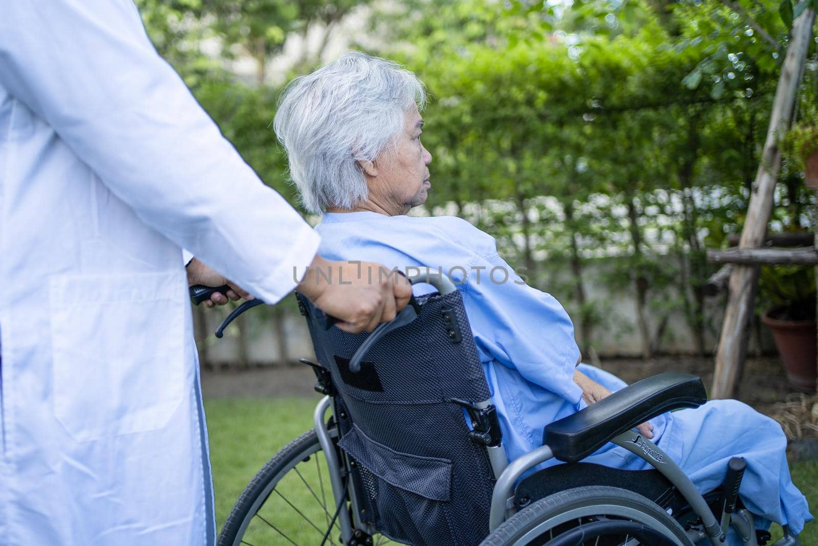 Doctor help and care Asian senior or elderly old lady woman patient sitting on wheelchair at park in nursing hospital ward, healthy strong medical concept. by pamai