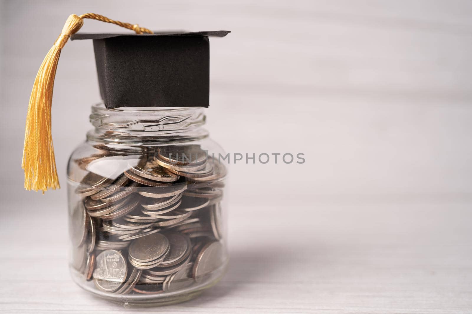 Graduation gap hat on coins money in jar for education fund; study learning concept.