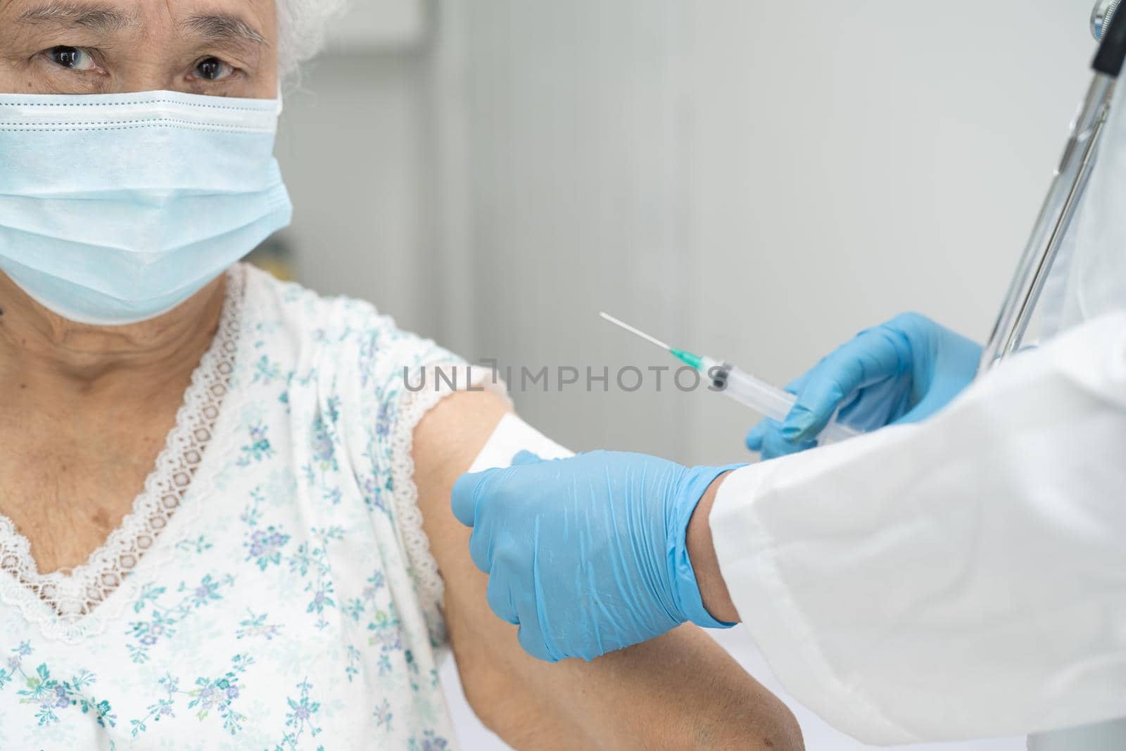 Elderly Asian senior woman wearing face mask getting covid-19 or coronavirus vaccine by doctor make injection.