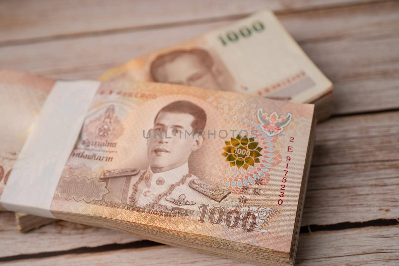 Stack of Thai baht banknotes on wooden background, business saving finance investment concept.