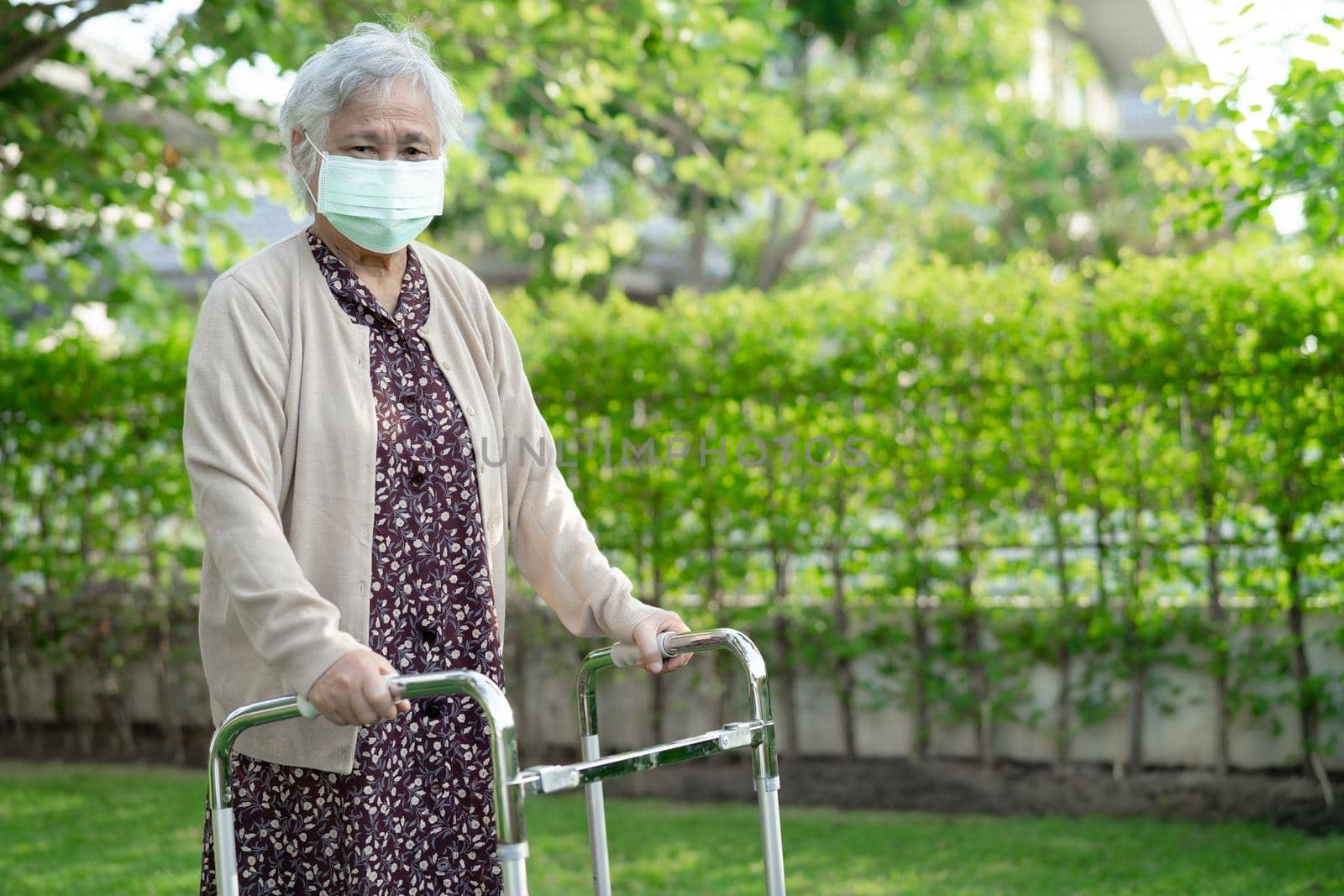 Asian senior or elderly old lady woman walk with walker and wearing a face mask for protect safety infection Covid-19 Coronavirus. by pamai