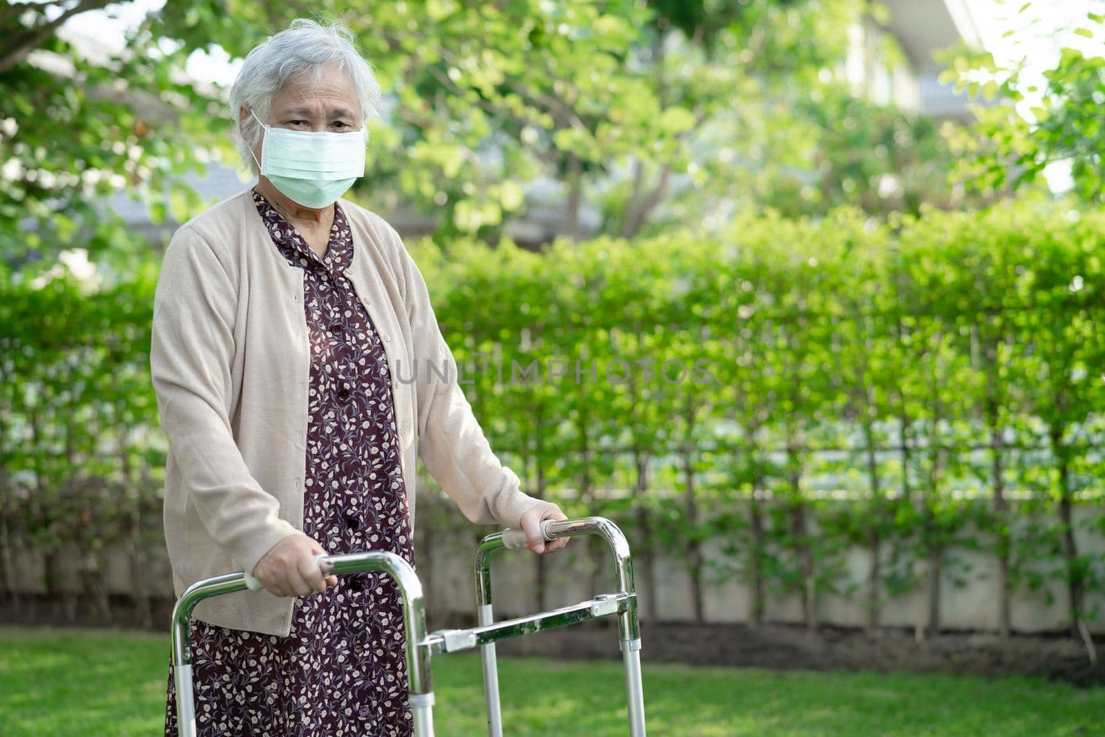 Asian senior or elderly old lady woman walk with walker and wearing a face mask for protect safety infection Covid-19 Coronavirus.