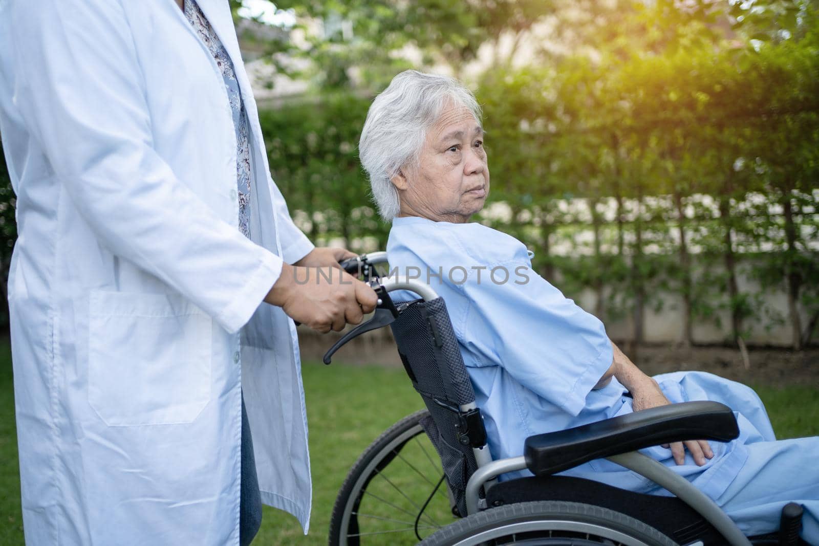 Doctor help and care Asian senior or elderly old lady woman patient sitting on wheelchair at park in nursing hospital ward, healthy strong medical concept.