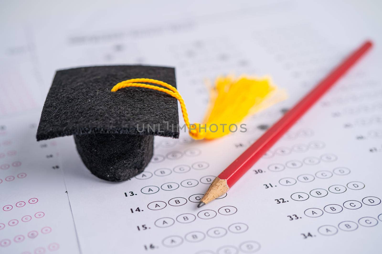 Graduation gap hat and pencil on answer sheet background, Education study testing learning teach concept. by pamai