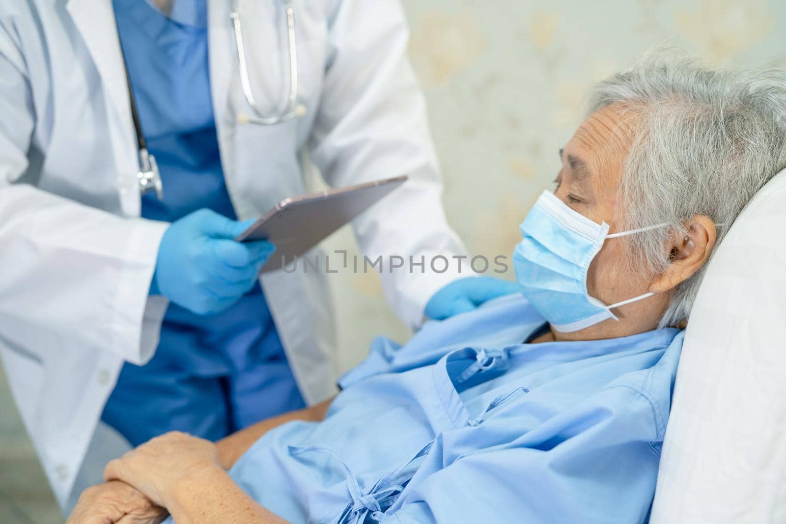 Asian doctor wearing face shield and PPE suit new normal to check patient protect safety infection Covid-19 Coronavirus outbreak at quarantine nursing hospital ward.