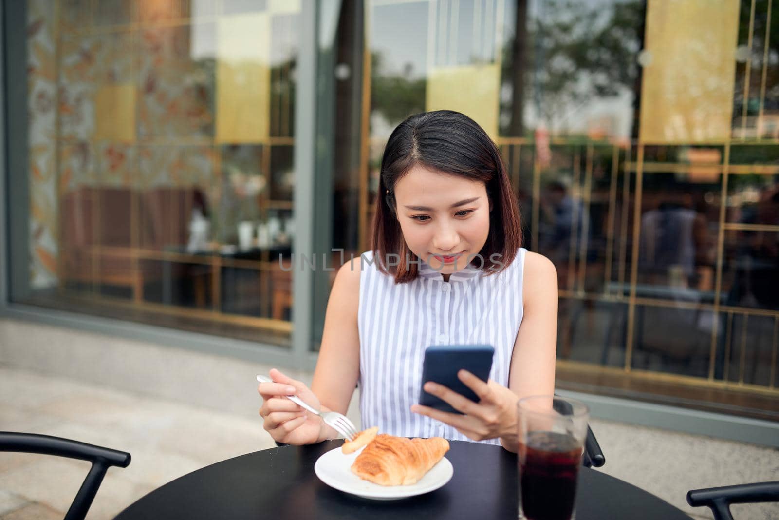 Portrait of beautiful young woman using smartphone while enjoying evening on outdoor coffee shop, copy space