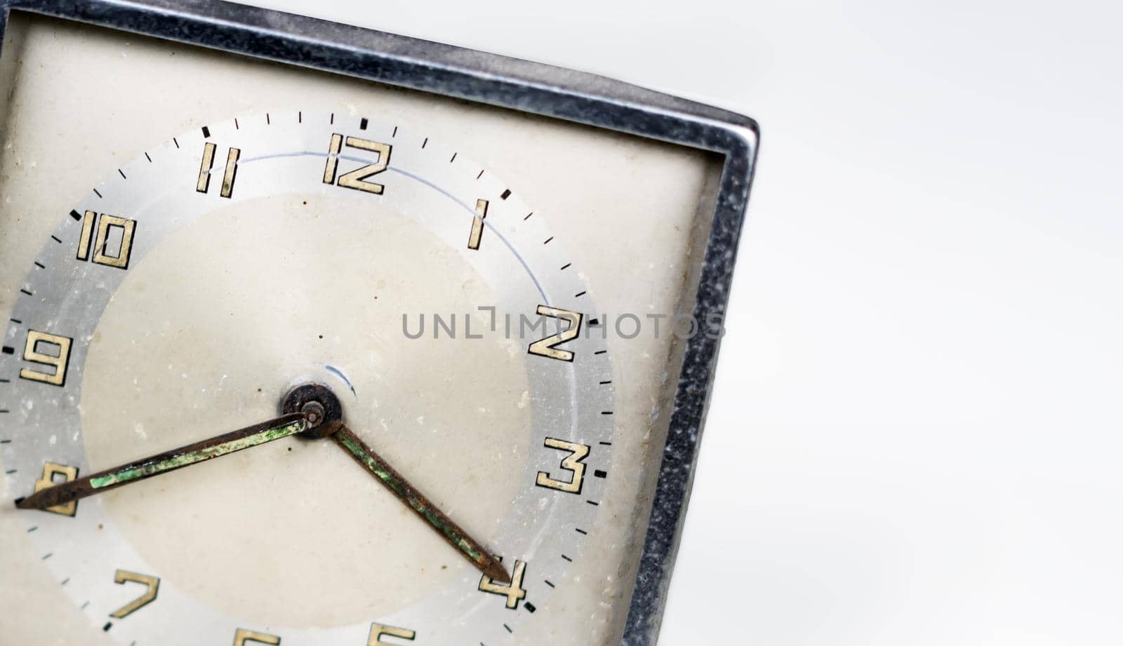 Old worn clock with square dial isolated on a white background. Analog time measurement. Vintage and retro object. Copy space.