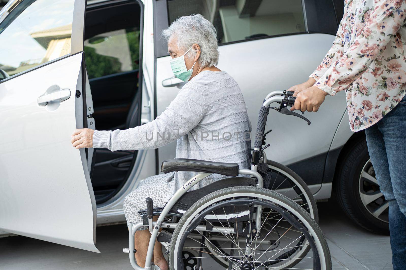 Help and support asian senior or elderly old lady woman patient sitting on wheelchair prepare get to her car, healthy strong medical concept. by pamai