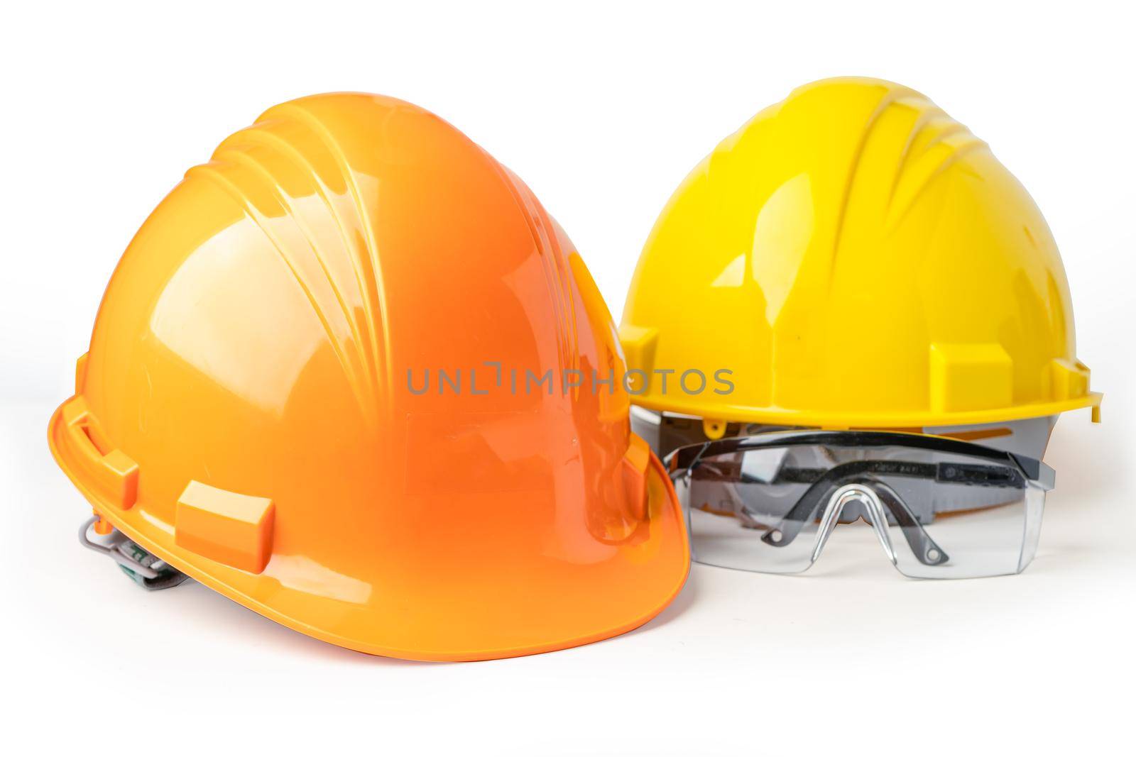 Yellow and orange construction helmet, safety glasses and magnifying glass isolated on white background with clipping path, engineer concept.