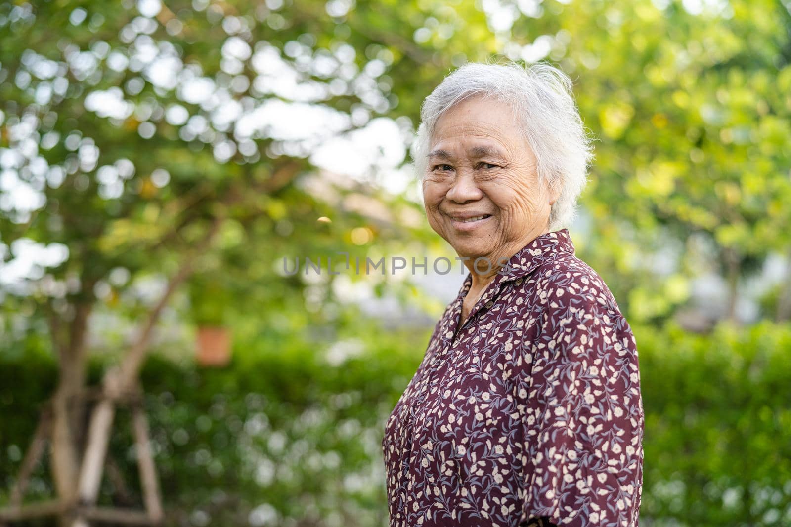 Asian senior or elderly old lady woman smile bright face with strong health while walking at park in holiday