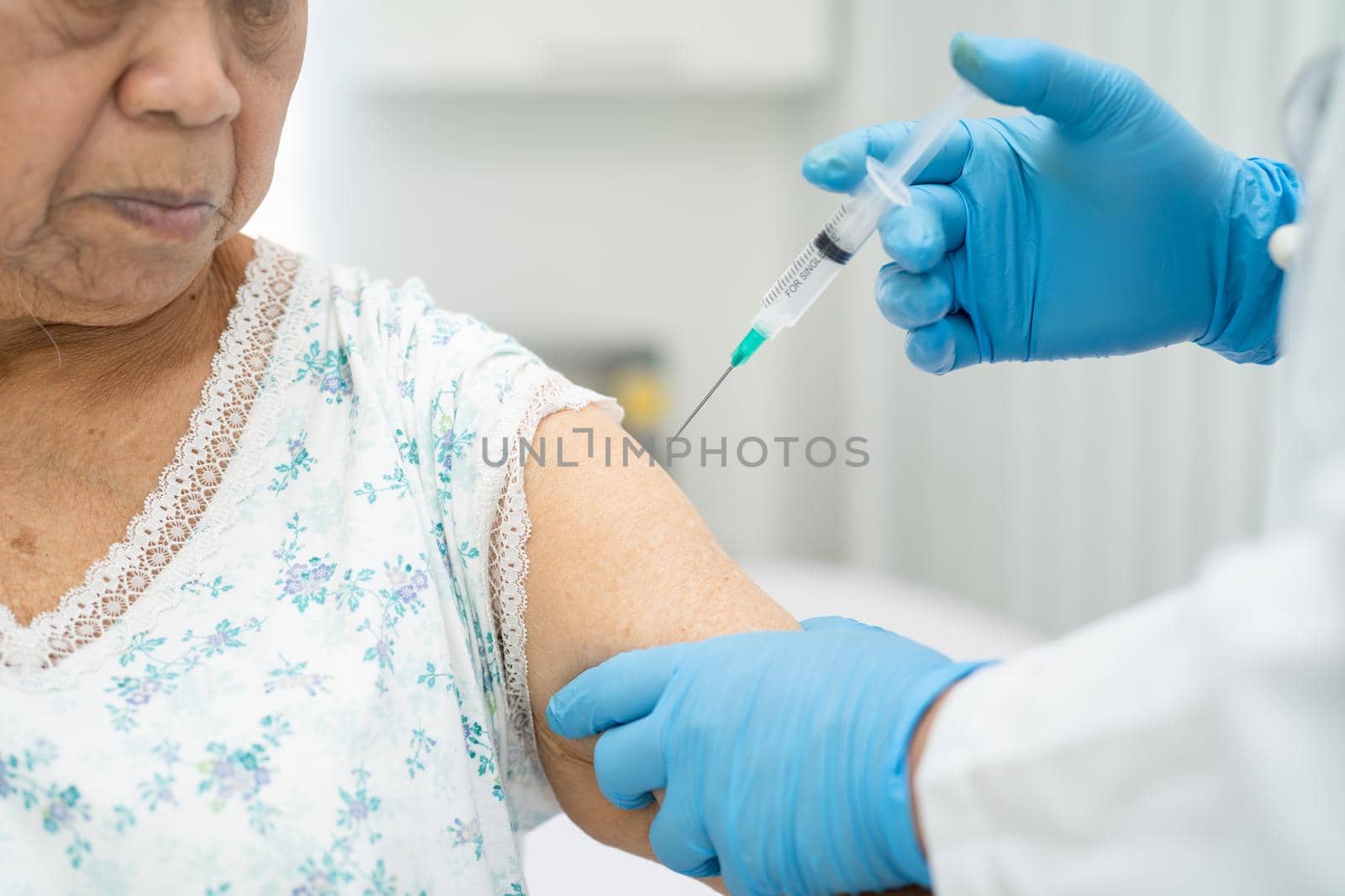 Elderly Asian senior woman wearing face mask getting covid-19 or coronavirus vaccine by doctor make injection.