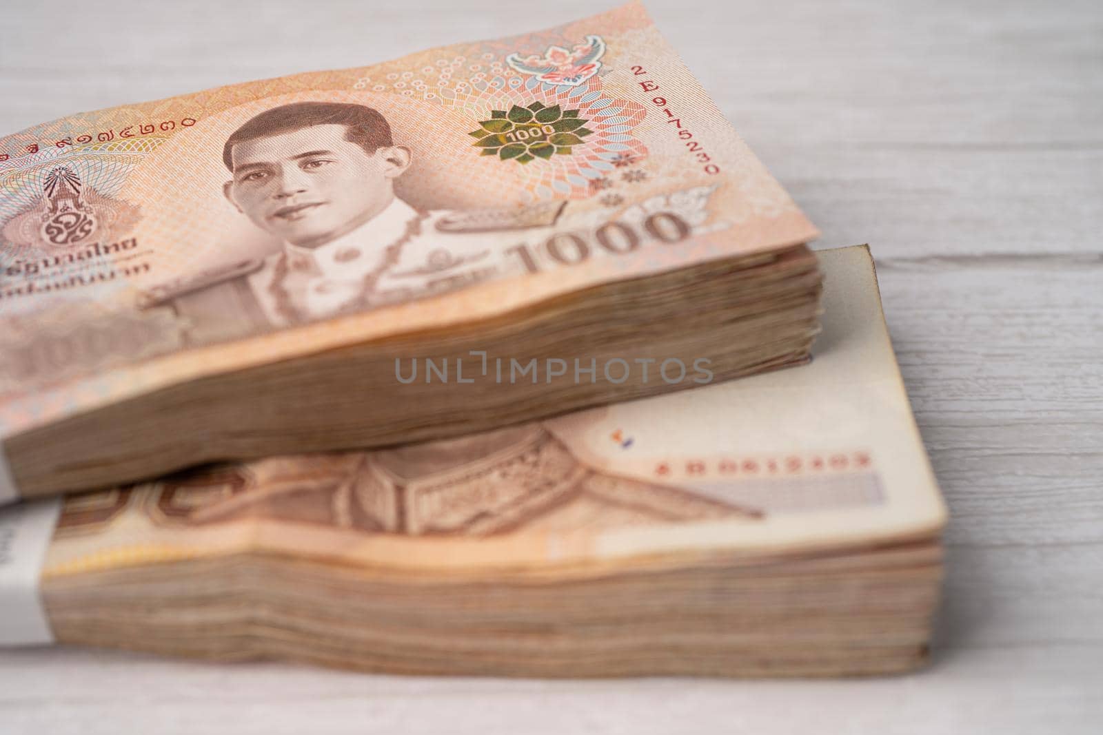 Stack of Thai baht banknotes on wooden background, business saving finance investment concept. by pamai