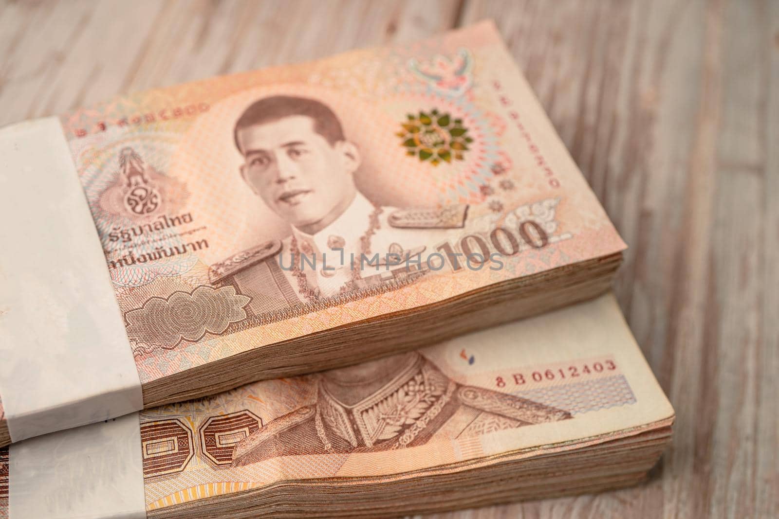 Stack of Thai baht banknotes on wooden background, business saving finance investment concept.