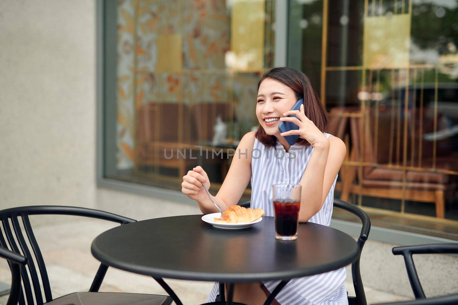 Elegant girl calling someone while resting in outdoor cafe by makidotvn