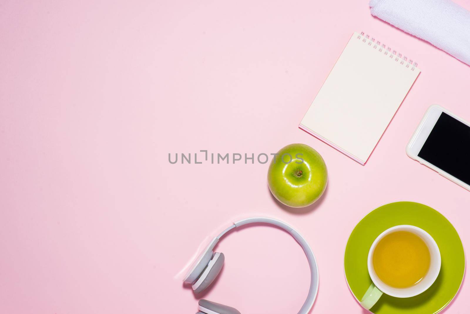 Healthy lifestyle concept. Sneakers, tea, apple and headphone on pastel color background. by makidotvn