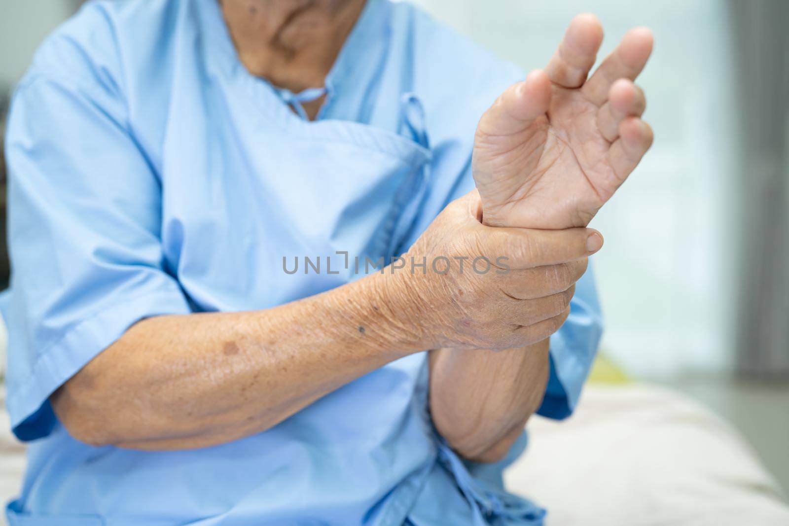 Asian senior or elderly old lady woman patient feel pain her wrist and hand on bed in nursing hospital ward, healthy strong medical concept. by pamai