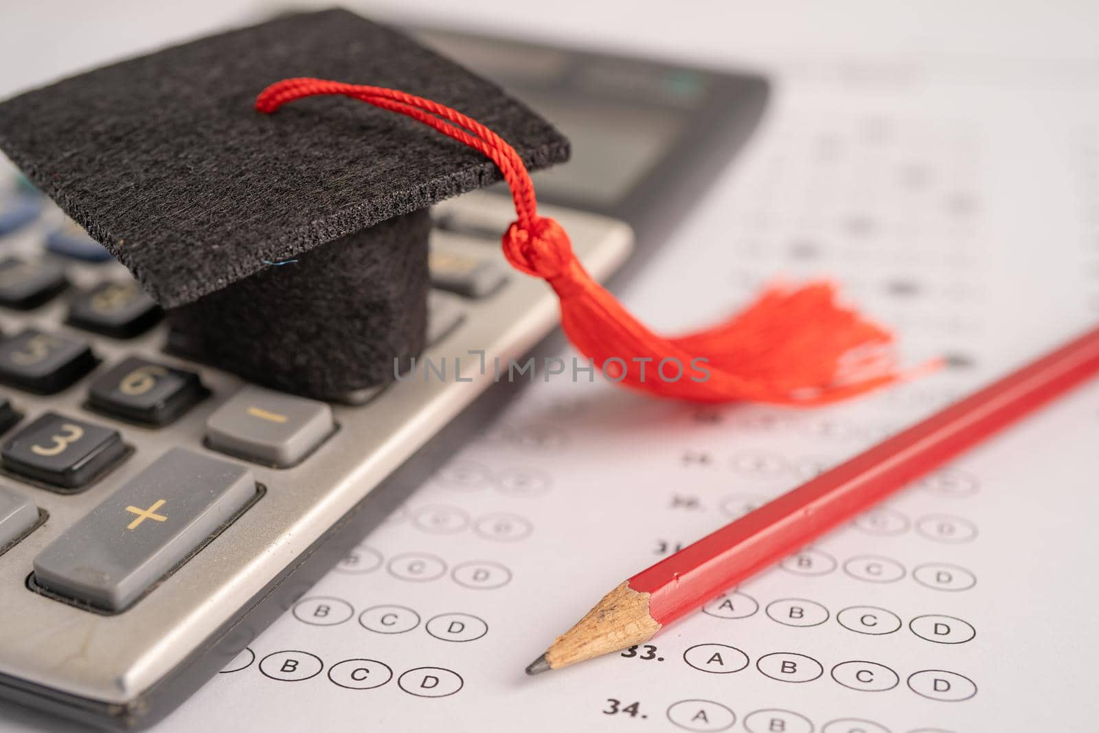 Graduation gap hat and pencil on answer sheet background : Education study testing learning teach concept.