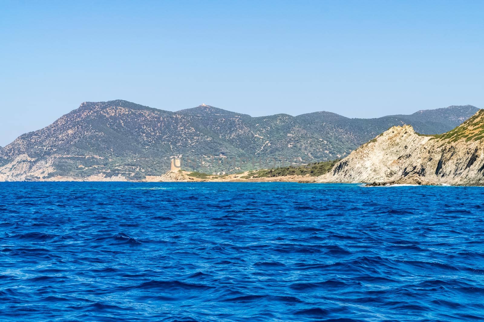 Beautiful view of the southern Sardinian sea from the boat. Note the historic Saracen tower on the rock formations.