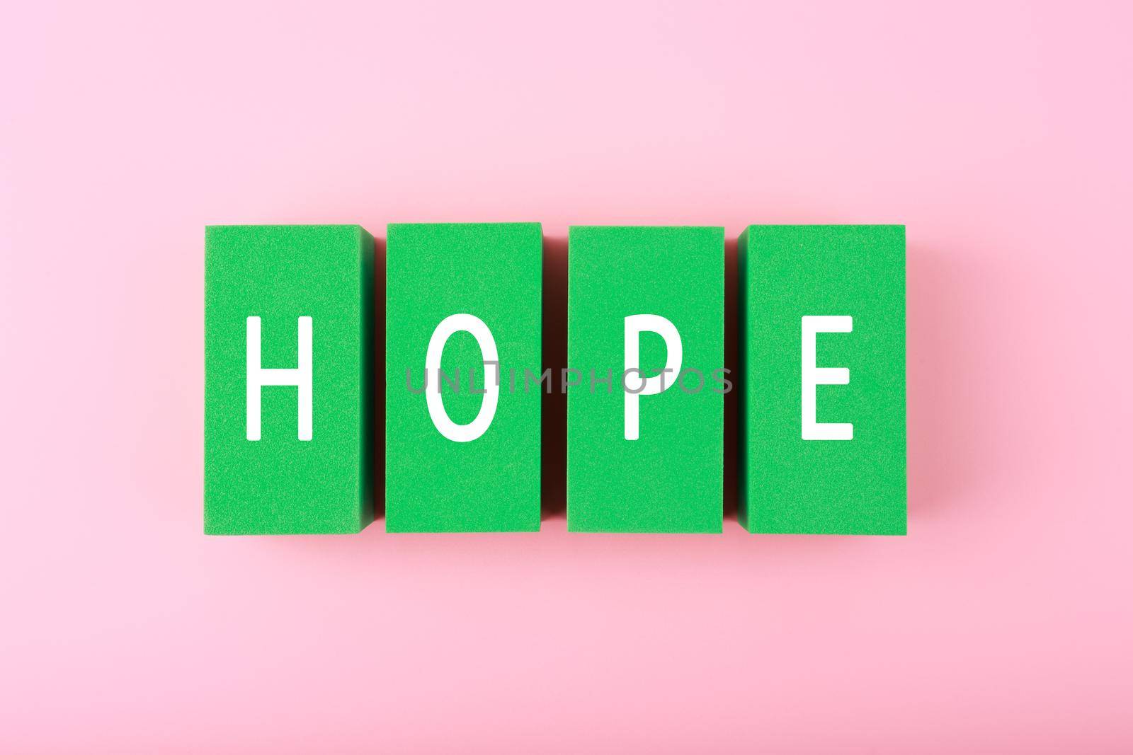 Concept of hope and faith. Minimal flat lay with hope single word written on green blocks against bright pink background. 