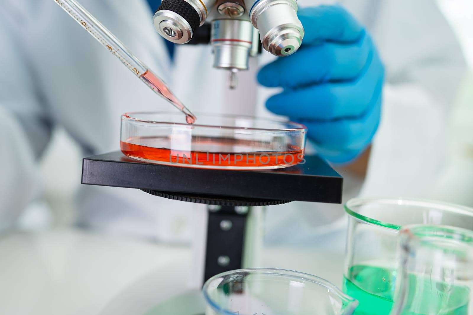 Asian scientist biochemist or microbiologist working research with a microscope in laboratory. For protect outbreak Coronavirus Covid19, bacteria and germs. by pamai