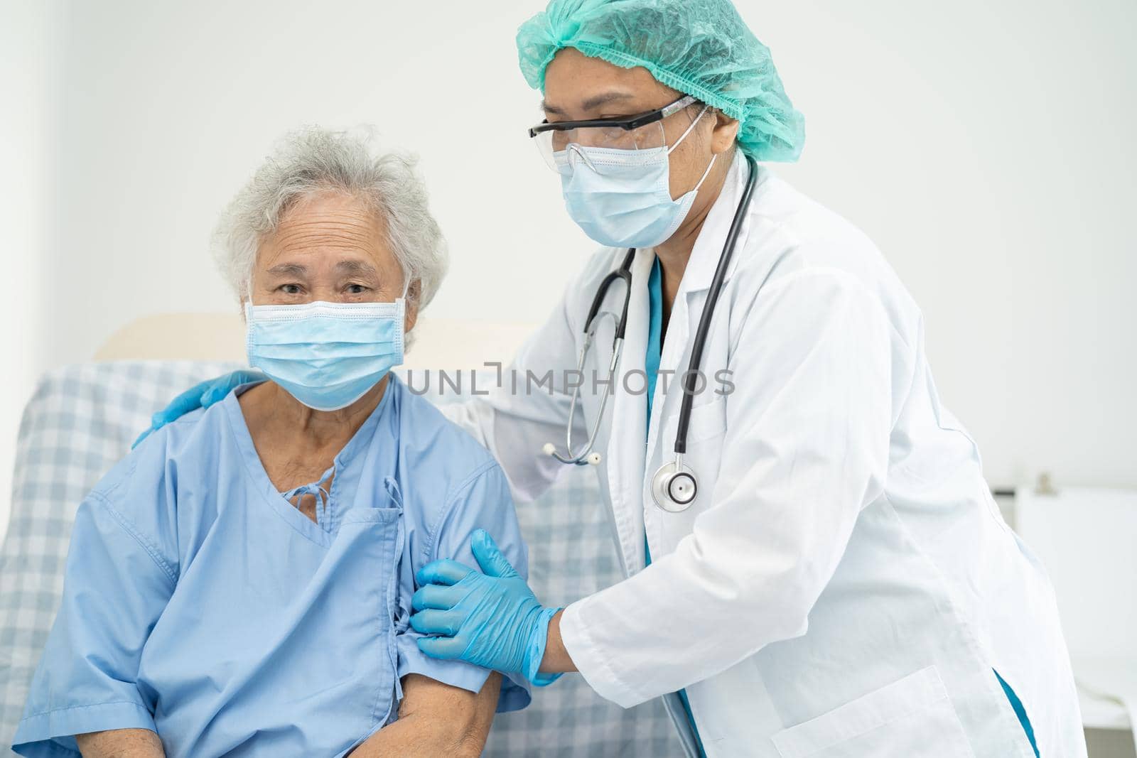 Doctor help Asian senior or elderly old lady woman patient wearing a face mask in hospital for protect safety infection and kill Covid-19 Coronavirus.