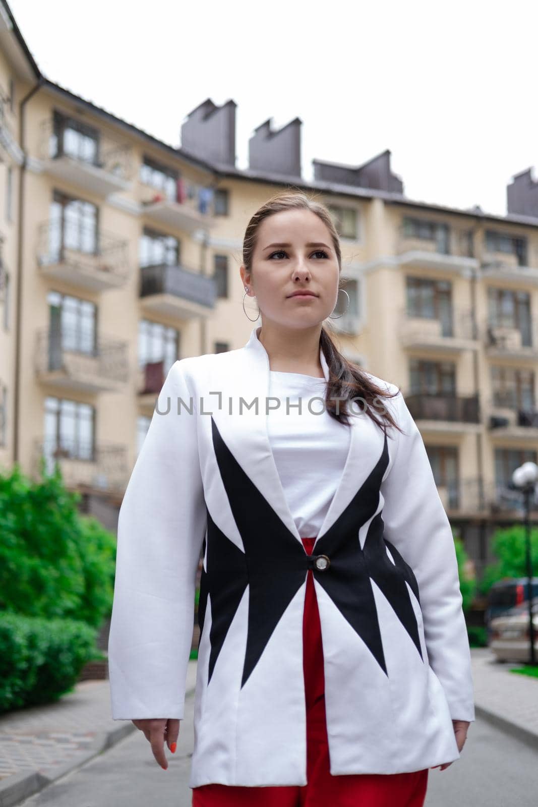 business woman in red pants, white blouse and jacket walking by the street.