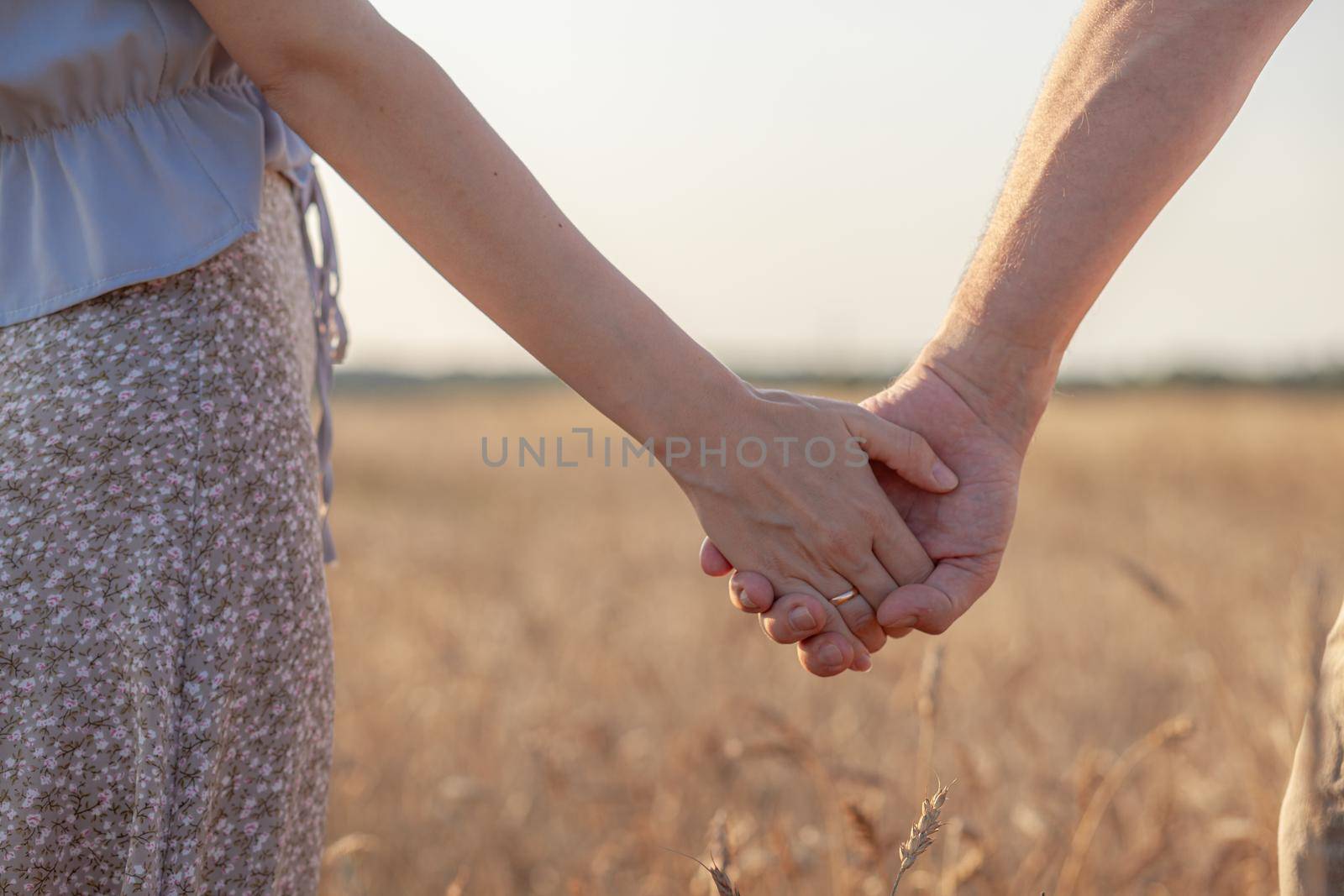 A couple holding hand during sunset, a symbol of love and happy by AnatoliiFoto