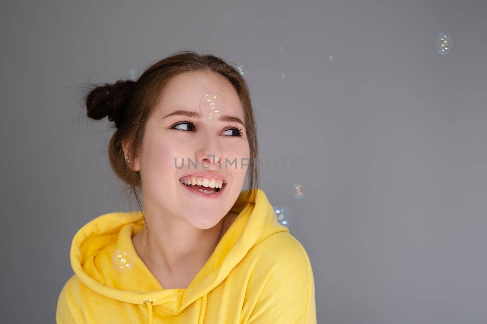 happy positive brunette in yellow hoodie in bright room. happy people. millennial generation. fashionable teenager. trendy colours.