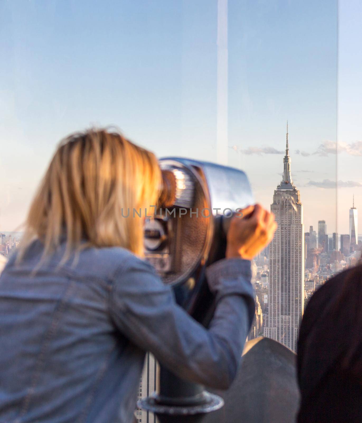 New york, USA - May 17, 2019: Rear View of Woman Peering Through Binocular View Finder at New York City Skyline from Top of the Rock