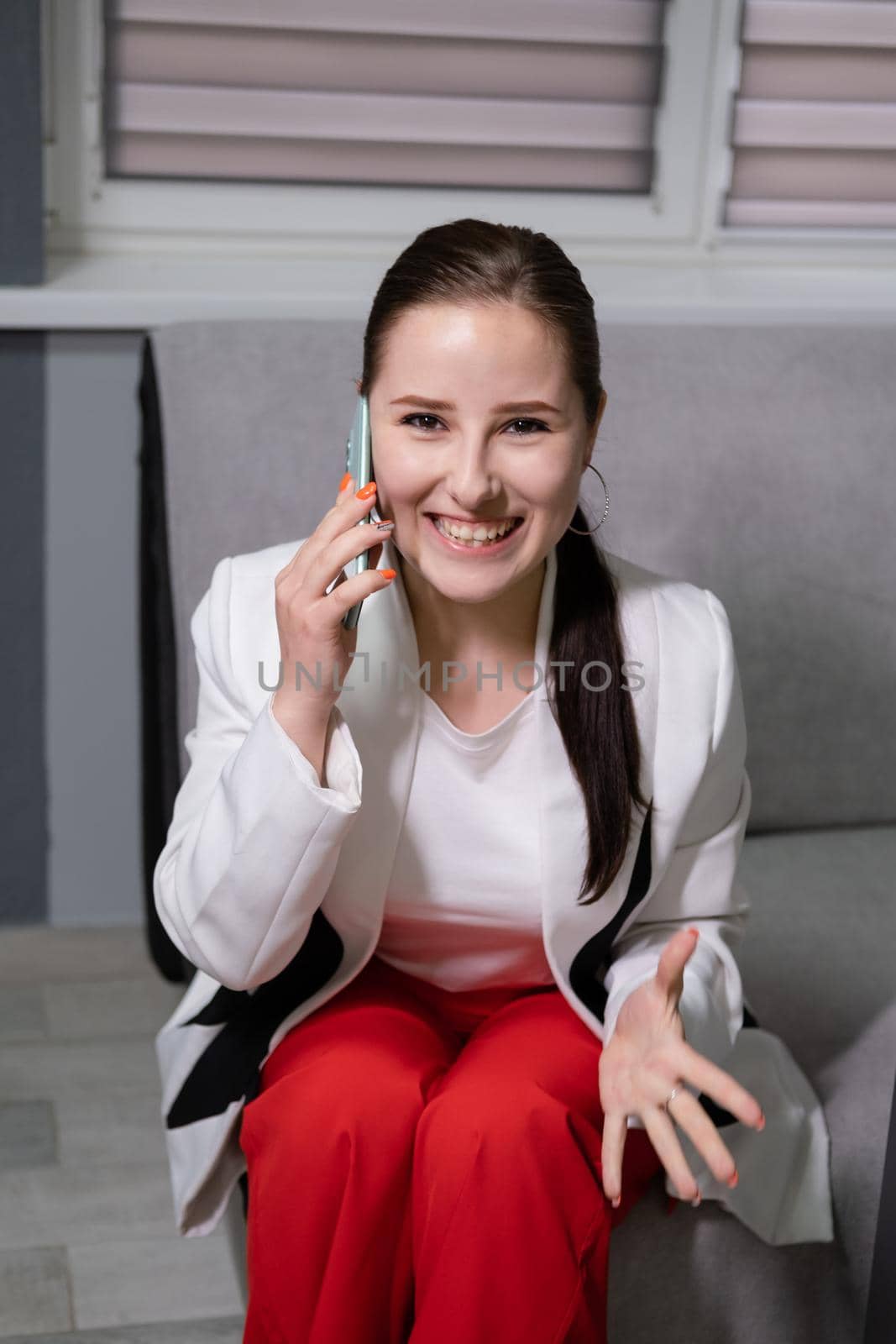 portrait of happy, surprised, excited brunette business woman talking by phone in gray office. gain, good phone call. success, victory, present.