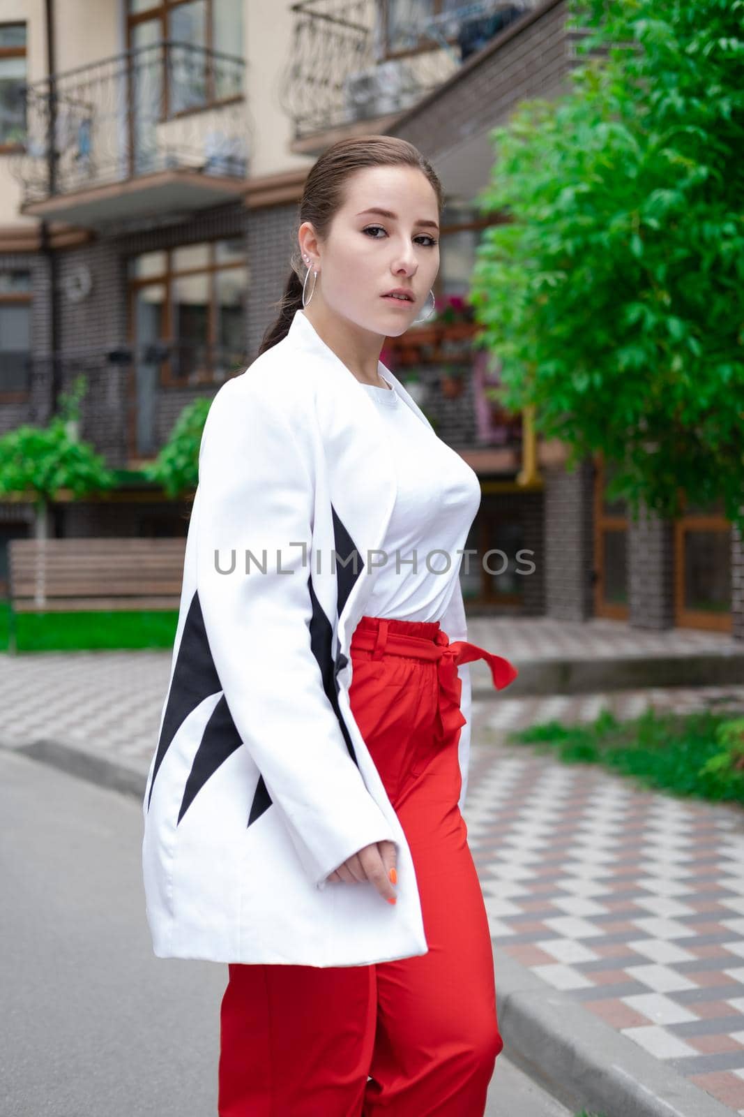 business woman in red pants, white blouse and jacket walking by the street by oliavesna