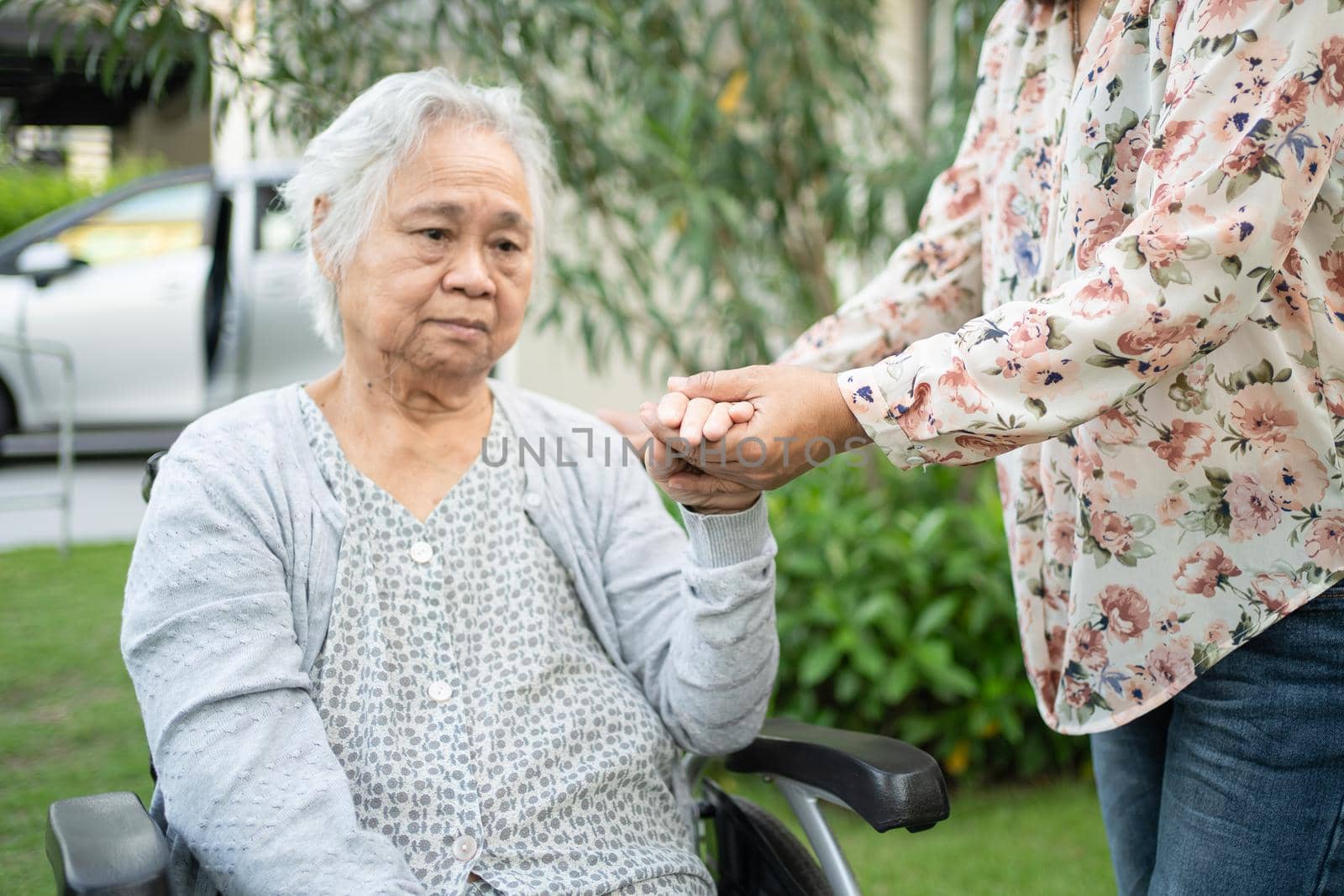 Help Asian senior or elderly old lady woman on wheelchair and wearing a face mask for protect safety infection Covid-19 Coronavirus in park.