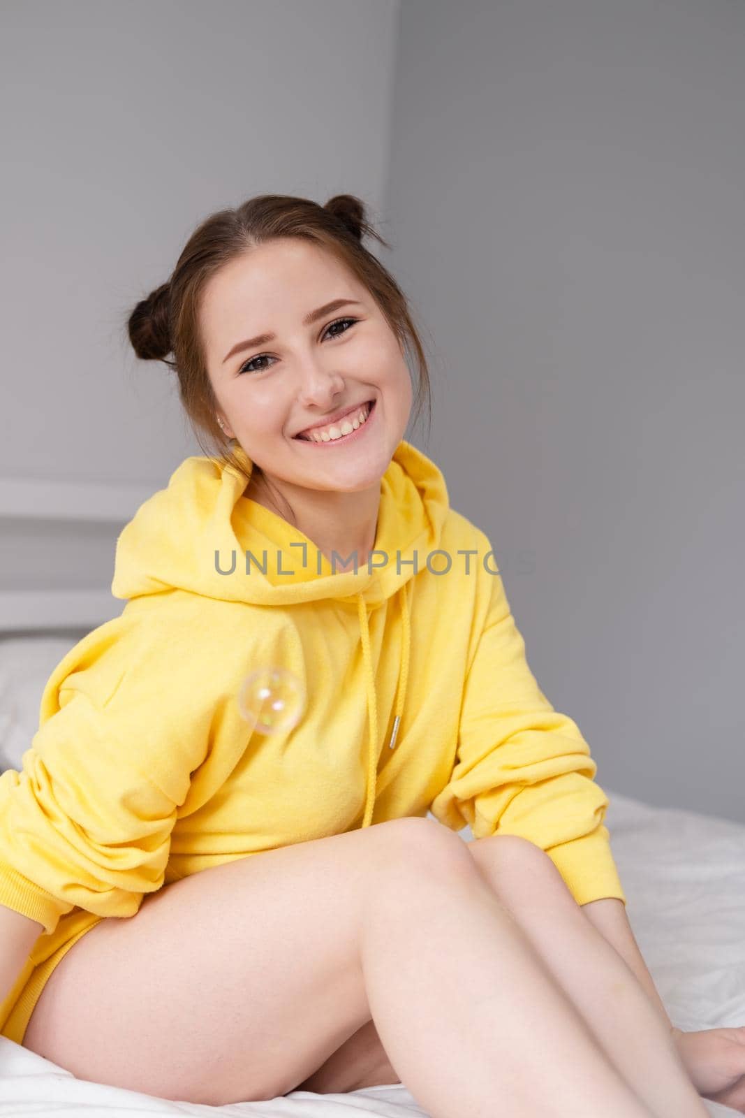 happy positive brunette in yellow hoodie in bright room. happy people. millennial generation. fashionable teenager. trendy colours by oliavesna