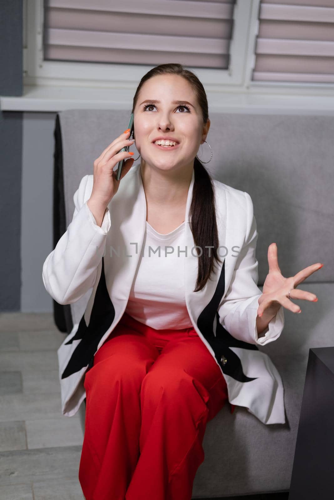 portrait of happy, surprised, excited brunette business woman talking by phone in gray office. gain, good phone call. success, victory, present by oliavesna