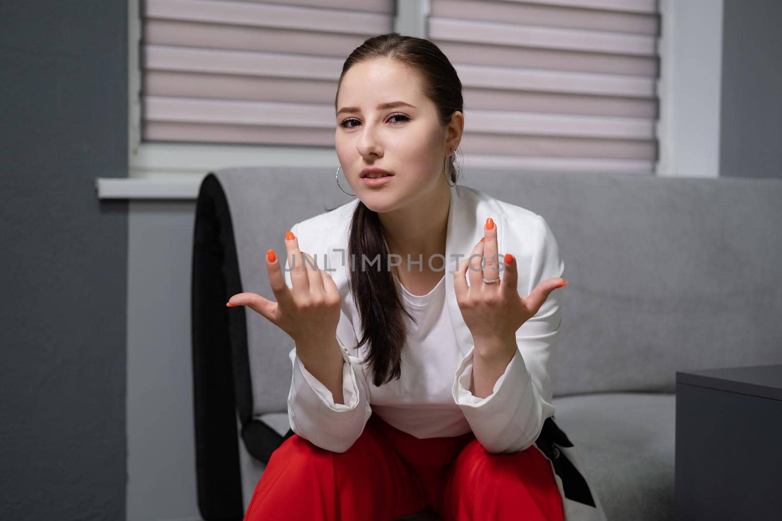 sexy business woman sitting by the table on couch in grey room - office. big boss. important, confident women. femininity. millennials.