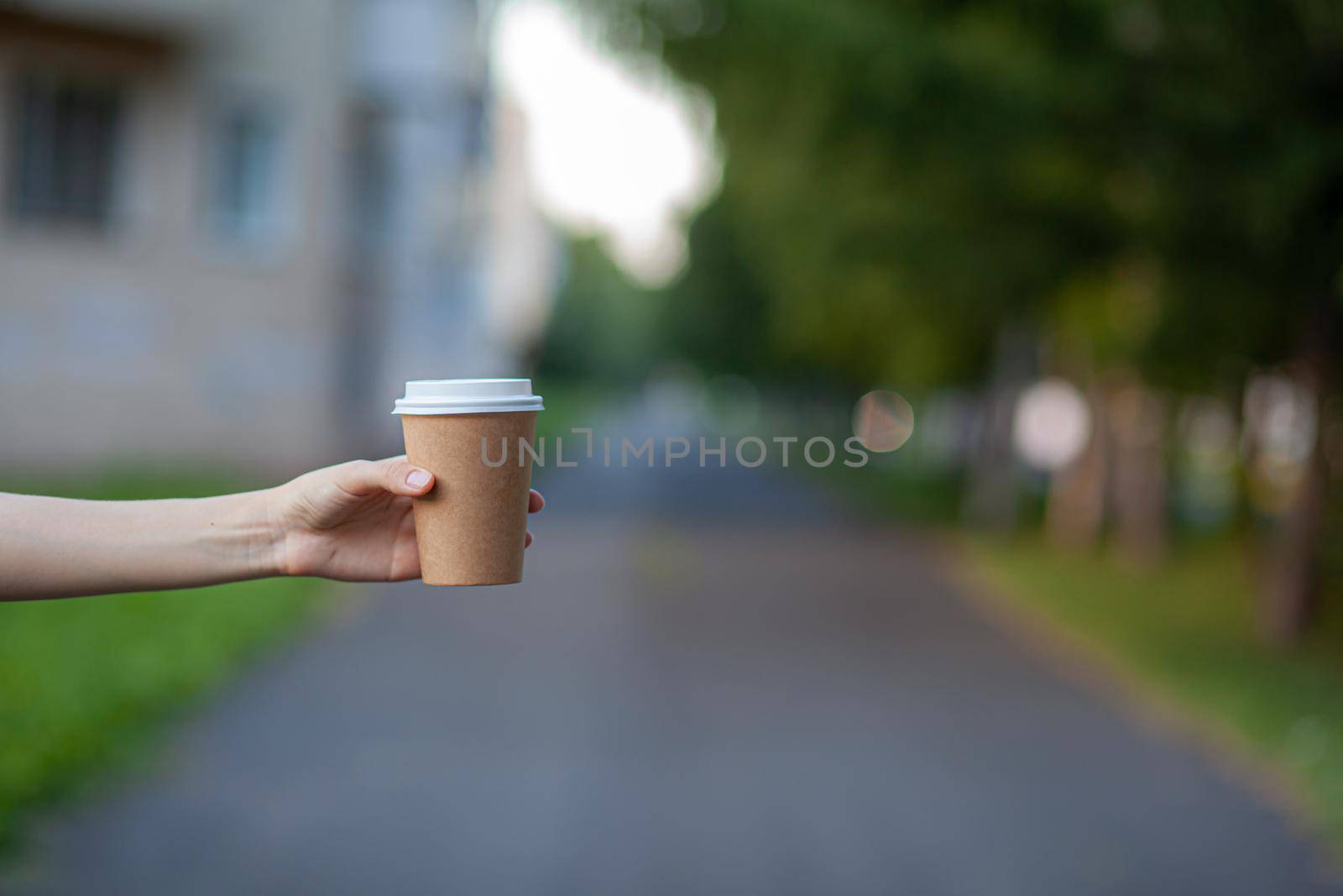 White paper cup with coffee in woman hand. Time for drink coffee in city. Coffee to go. Enjoy moment, take a break. Disposable paper cup closeup. Delicious hot beverage. Blank space for text, mockup